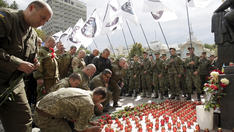 Ukrainian soldier hold flowers as they attend a memorial service for their fallen comrades in front of Ukrainian Parliament
