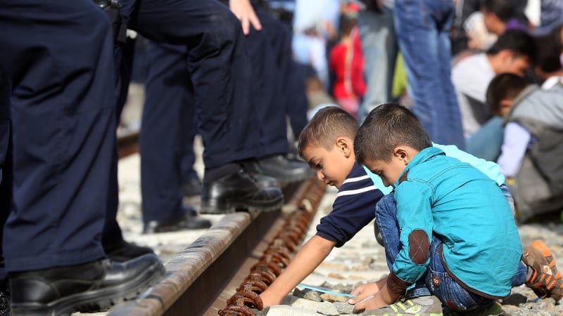 Children play near policemen standing guard at a railway station near the official border between Serbia and Croatia