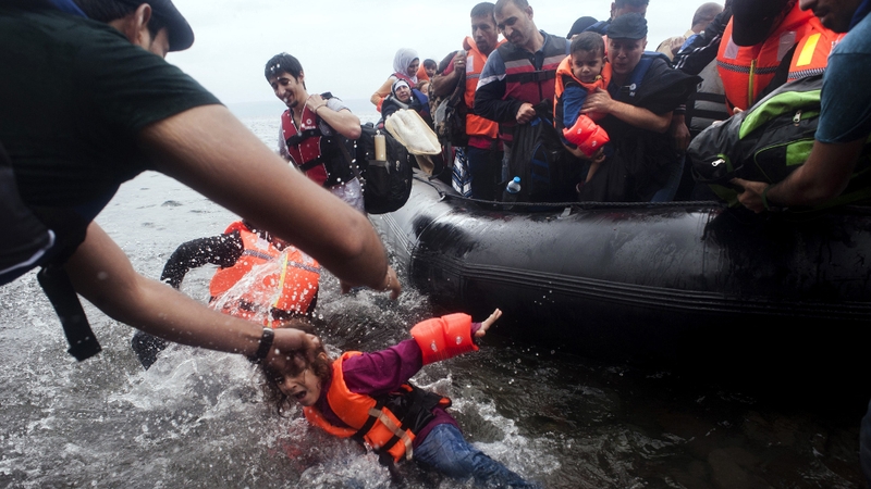 A young girl falls in the water as a boat carrying refugees lands on the beach at Sykamia on the Greek island of Lesbo