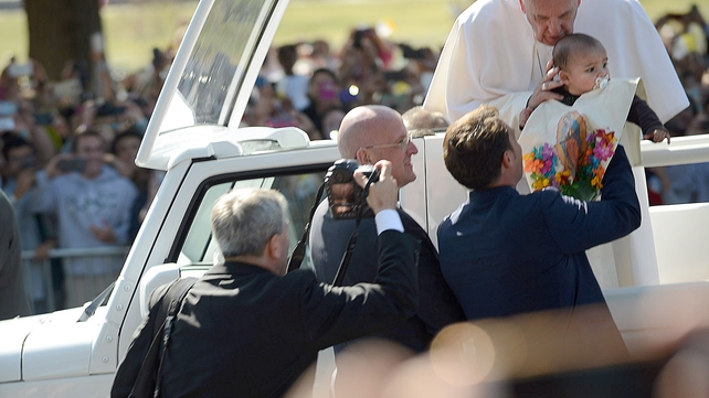 Pope Francis blesses a child handed to him during a parade on the National Mall, Washington DC