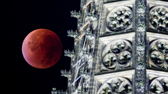 The supermoon appears beside a spire of the Cologne cathedral during a total lunar eclipse over Cologne, Germany