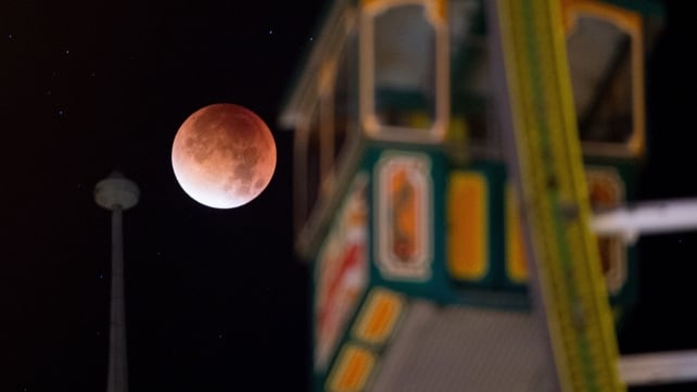 The supermoon, appears red behind a gondola of a ferris wheel in Erfurt, Germany