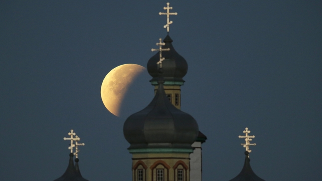 The supermoon during a lunar eclipse in the sky above a church in Turets village outside Belarus