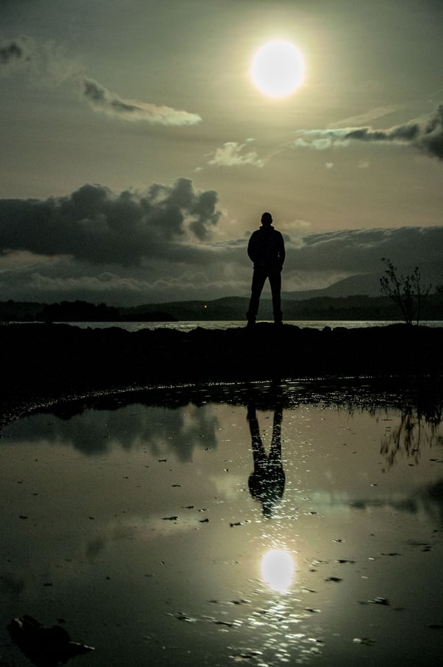 A person staring out over the lower lake in Killarney Co Kerry, while their reflection is captured in a pond
