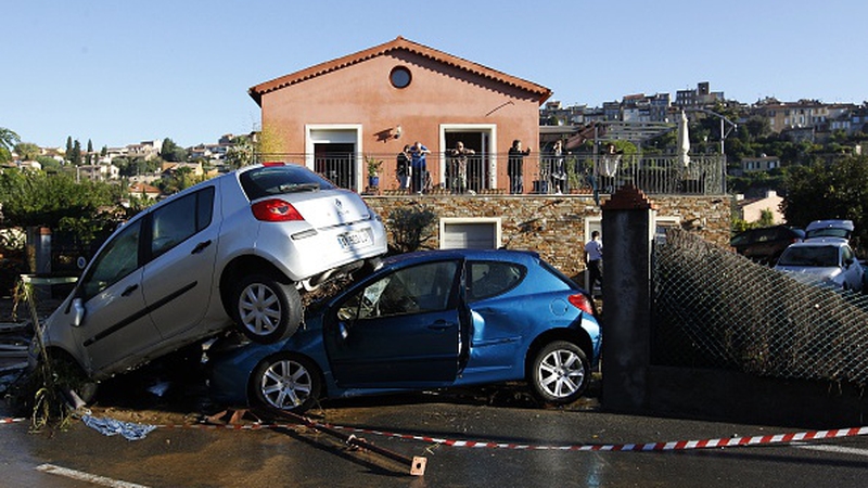 People look at the rubble and damaged cars in front of their house in Biot, France
