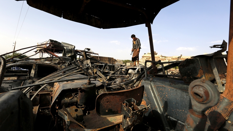 A Yemeni man stands on a vehicle destroyed by a Saudi-led air strike