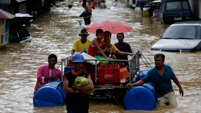 Locals ride on a makeshift raft at a flooded street in Cabanatuan city, northern Manila
