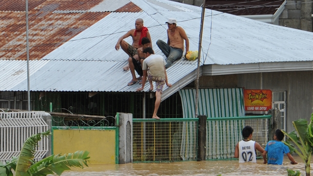 Residents sit on the roof of their house in Santa Rosa, north of Manila