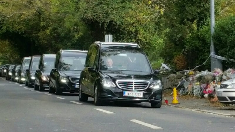 The funeral procession passes the scene of the fatal fire