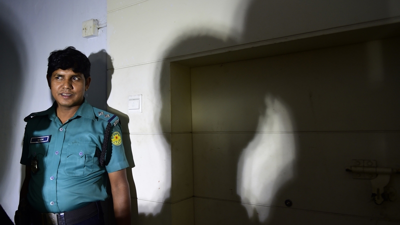A policewoman stands outside the office where Faysal Arefin was hacked to death
