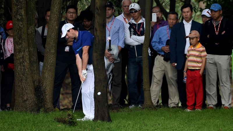 McIlroy shoots from behind a tree during a trying second round in China