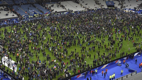 Confused supporters gather on the pitch in Paris