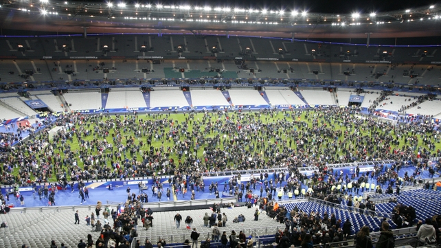 Spectators wait on the pitch of the Stade de France stadium in Paris after two explosions outside the national stadium