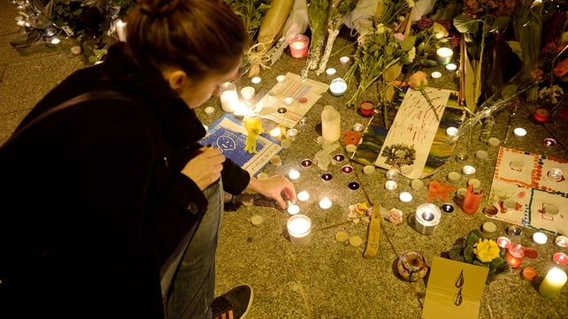 A woman lights candles outside Le Carillon bar in Paris