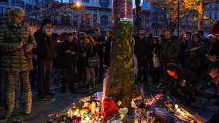 People place flowers and candles in memory of the victims of Friday's attack in front of Bataclan concert hall 
in Paris