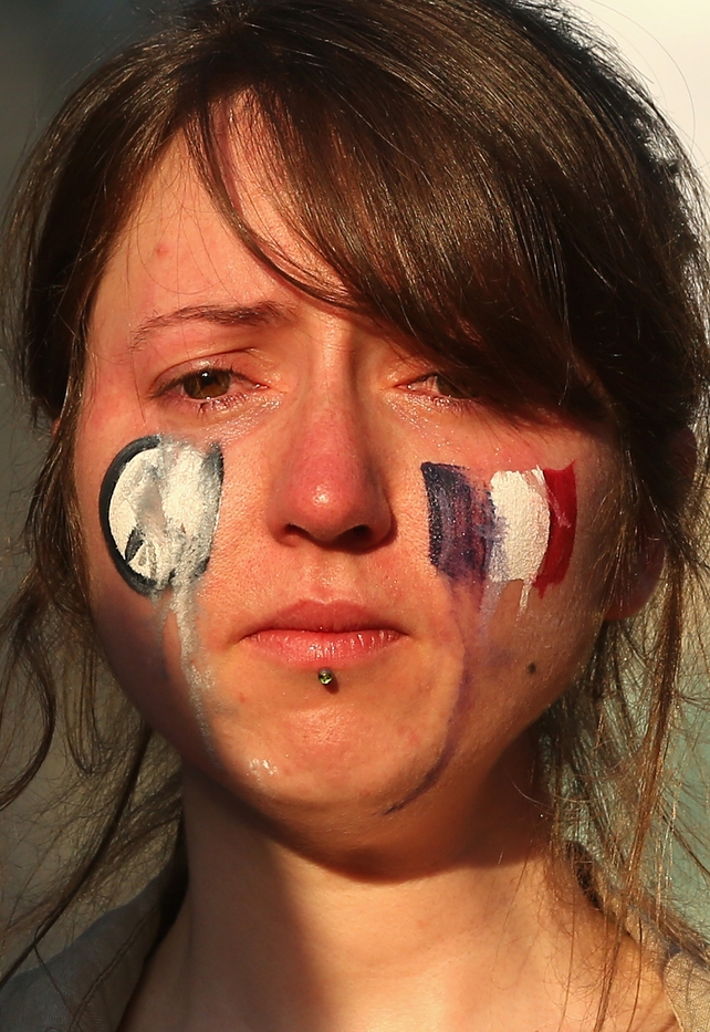 Tears run down the face of a woman at a vigil at Federation Square, Melbourne, Australia