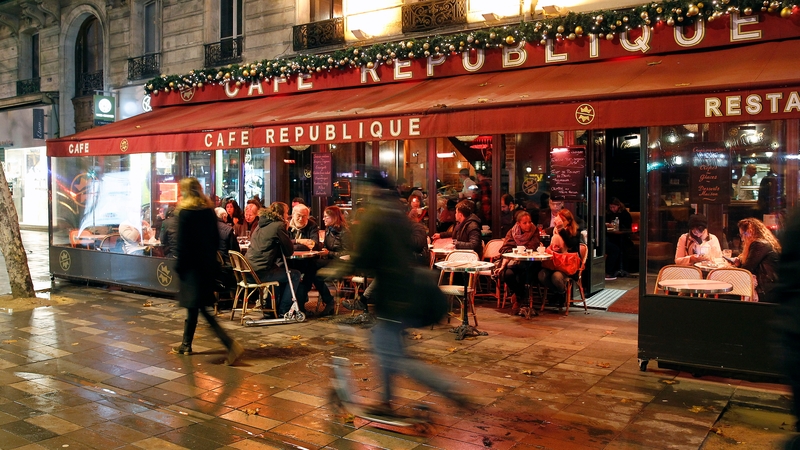 People sit outside a restaurant in the 11th district of Paris one week after a series of terrorist attacks
