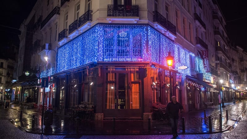 A man walks in an empty street in front of the closed Le Roi des Belges bar in Brussels city centre