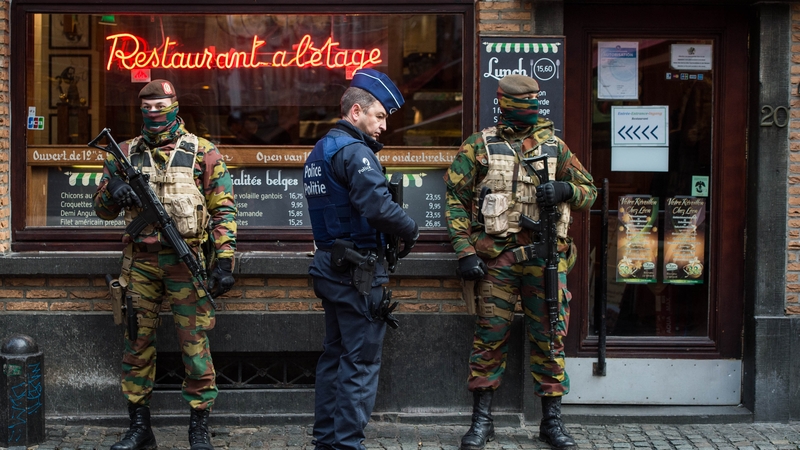 A police officer and soldiers stand guard on the streets of Brussels following the terror alert level being raised