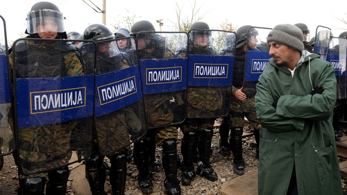 A refugee looks at riot police during the protest on the Greek border with Macedonia