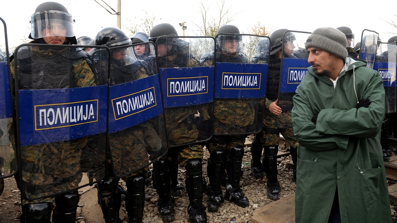 A refugee looks at riot police during the protest on the Greek border with Macedonia