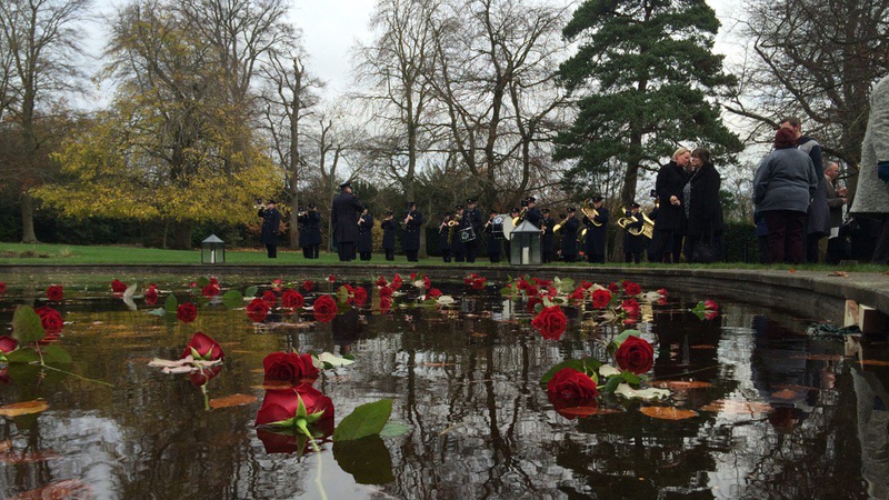 Roses are cast on the pond at Farmleigh for the missing as the Garda Band plays