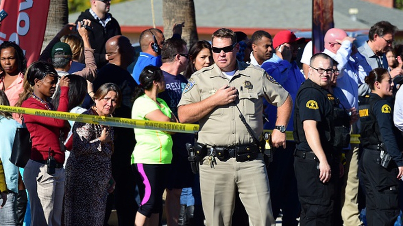 A crowd gathers behind a police line near the scene of the shooting
