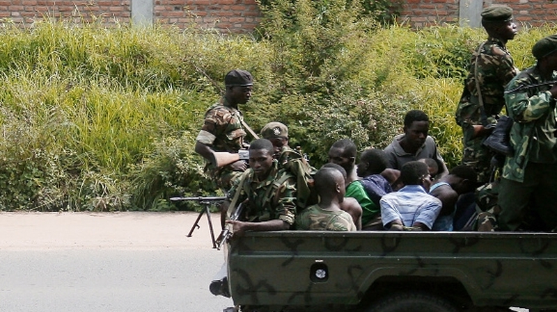 A military vehicle carrying men, who are tied up, drives through the city of Bujumbura