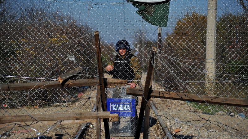 A border control policeman stands behind a fence at the borders in Idomeni village, northern Greece