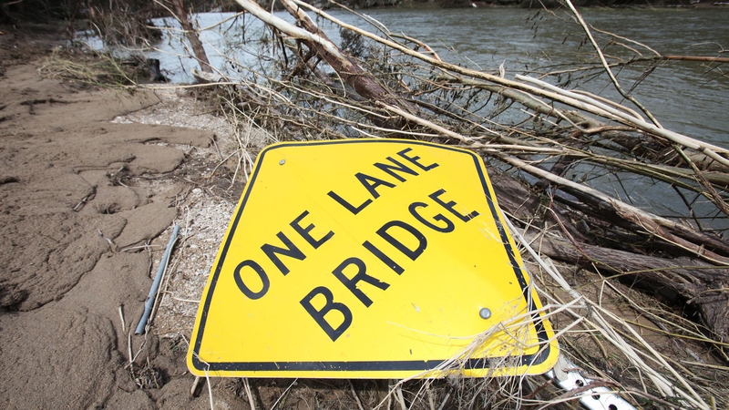 Debris and a road sign sit on the bank of the Blanco River in Wimberley, Texas