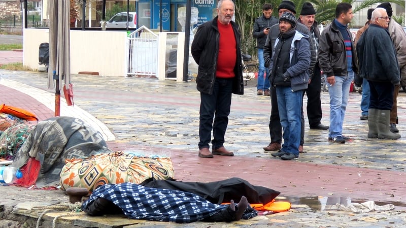 People stand near washed up bodies of drowned refugees in Ayvalik, Turkey