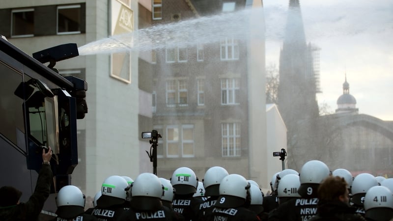 A water cannon sprays water at right-wing demonstrators next to police officers in Cologne, Germany