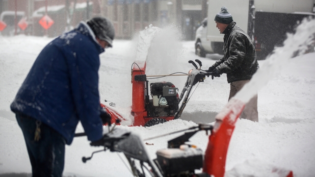 Workers struggle to clear snow from a footpath in Washington