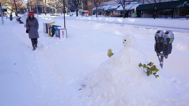 A woman walks on a sidewalk near a snowman in front of a hotel in Washington DC