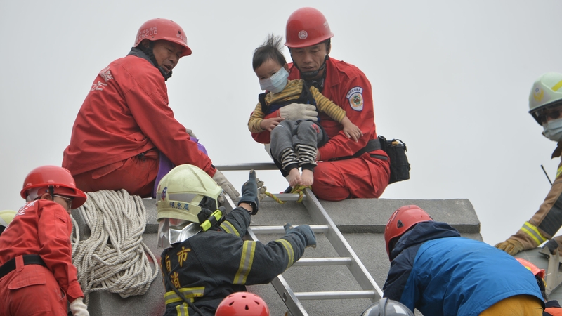 Rescue personnel help a young victim at the site of a collapsed building