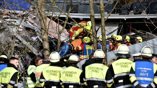 An injured passenger is removed from the crumbled trains