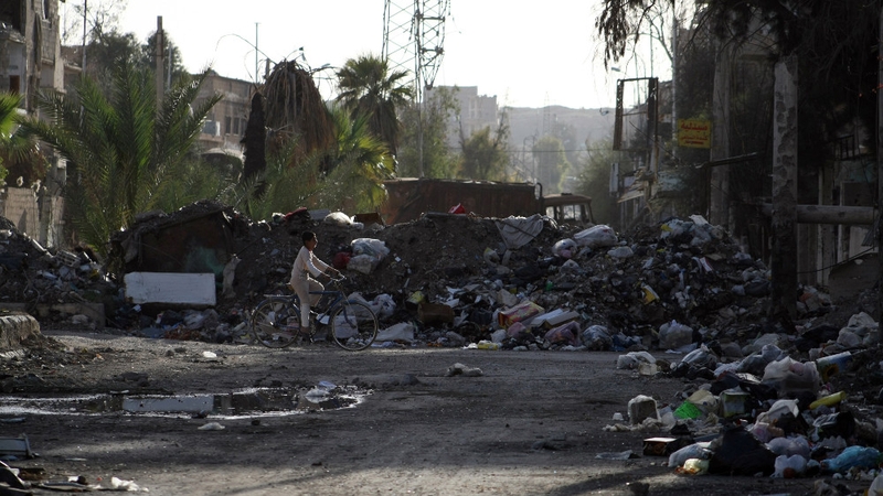 A child cycles by piles of rubbish in the besieged town of Deir ez-Zor