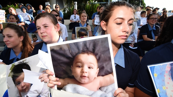 Students hold photographs of baby Asha during a protest outside the Lady Cilento Children's Hospital in Brisbane