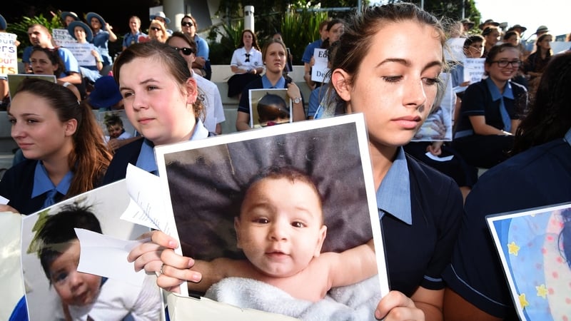 Students hold photographs of baby Asha during a protest outside the Lady Cilento Children's Hospital in Brisbane