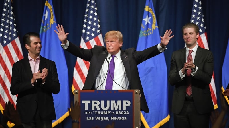 Donald Trump speaks as his sons Donald Trump Jr (L) and Eric Trump (R) look on during the caucus