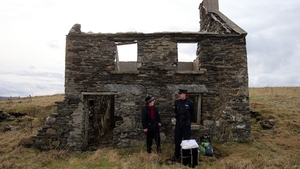Presiding Officer Carmel McBride and Garda Sergeant Paul McGee stand with a ballot box outside an abandoned home on the island of Inishbofin, Co Galway, awaiting the arrival of a helicopter to take them back to the mainland