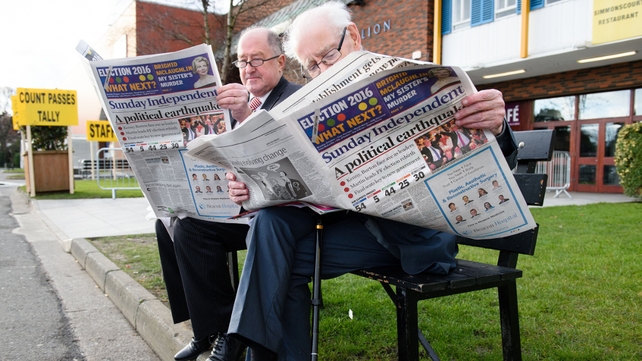 Fianna Fail officials read the morning newspapers as they wait outside the count centre in Dublin
