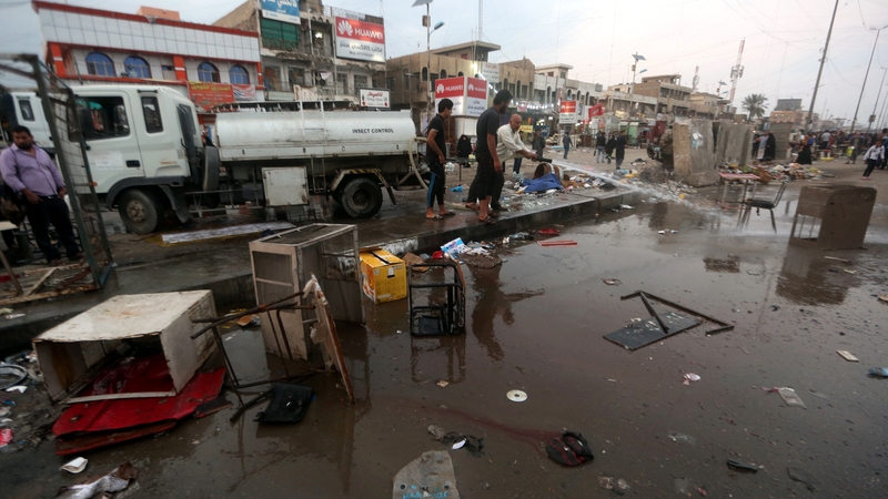 Iraqi men clean up the site following the bombing near a market in the Sadr City area of northern Baghdad