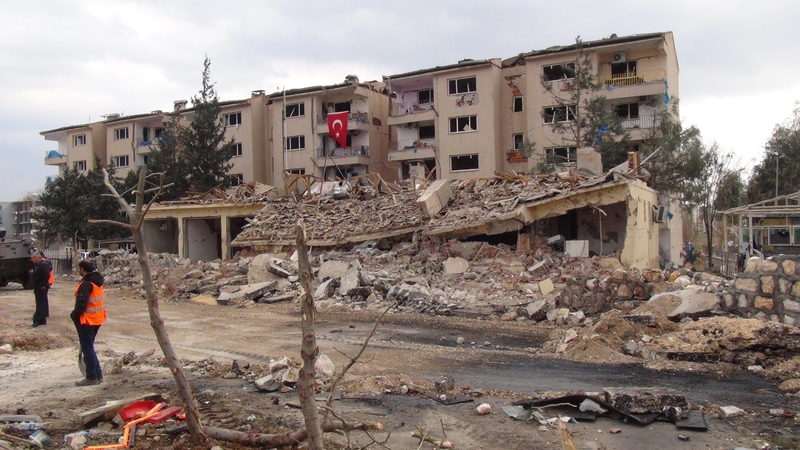 Turkish police officers stand in front of a damaged building after an attack in the southeastern province of Mardin