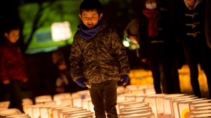 A boy walks past the paper lanterns at Natori City Office