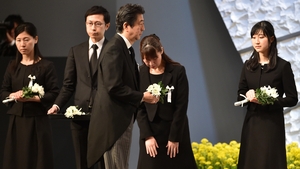 Japanese PM Shinzo Abe (C) holds a chrysanthemum as an offering for the victims of the earthquake and tsunami