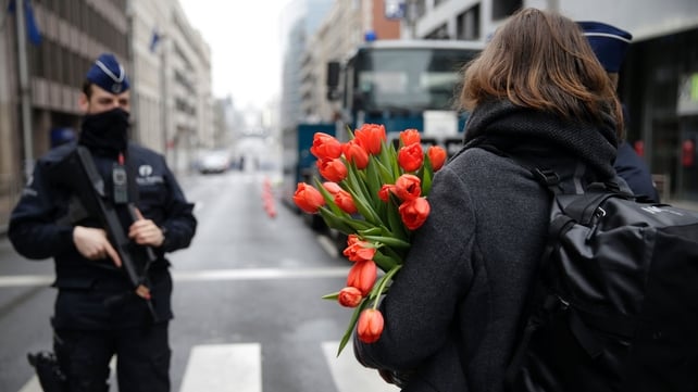 A woman arrives with flowers at a cordoned-off area near Maalbeek Metro Station, where one of the bombs was detonated