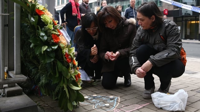 Women light candles to place with flowers near Maalbeek metro station