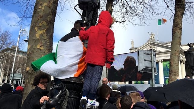 Children climb a lamppost for a better view of the parade