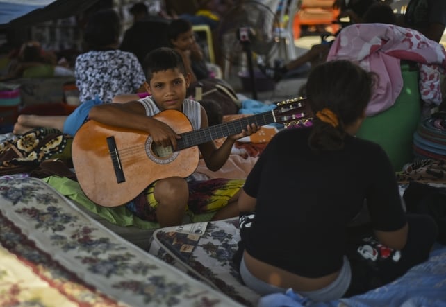 A boy plays his guitar at the shelter in Manta